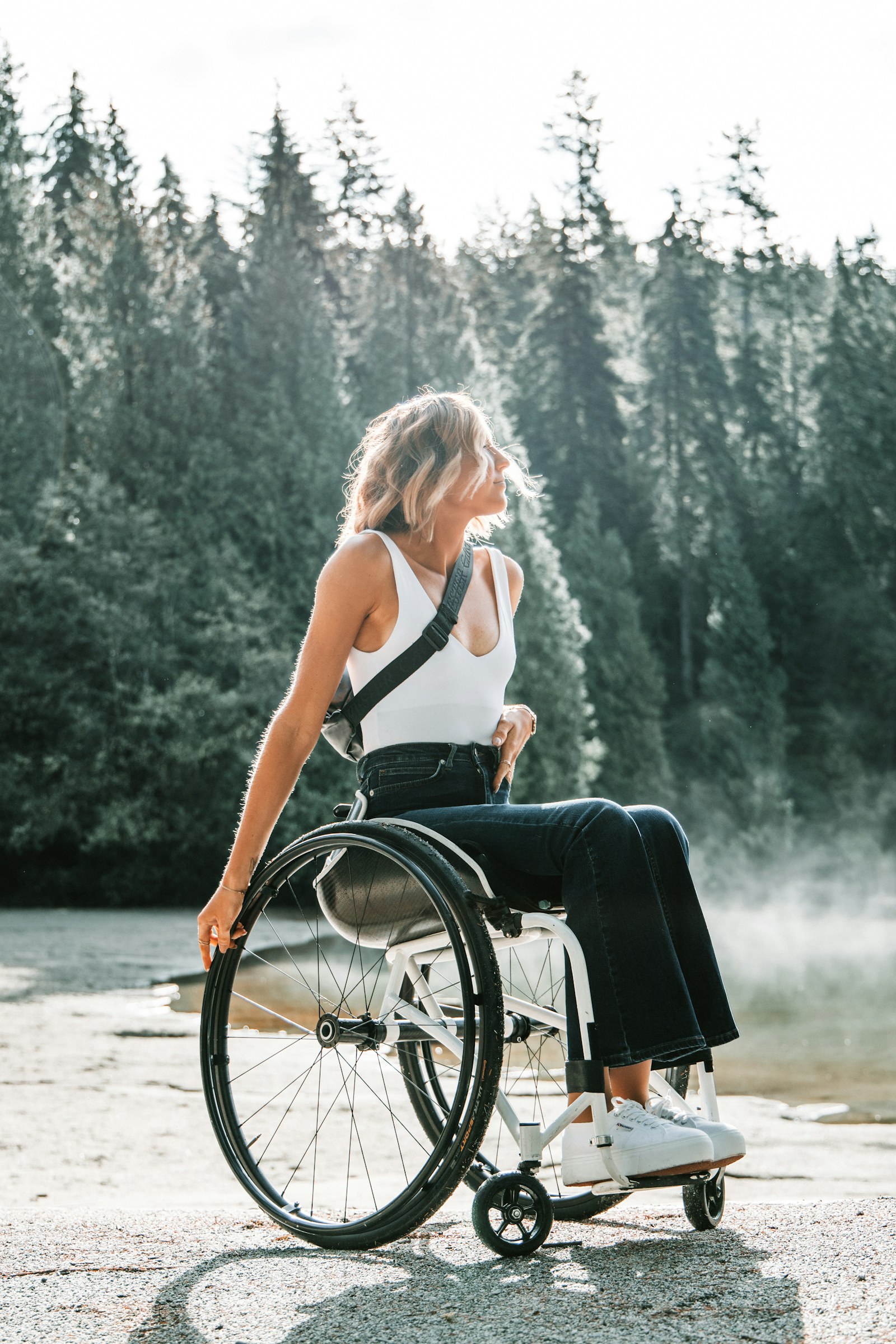 A woman in a wheelchair outdoors by a lake, confident and independent